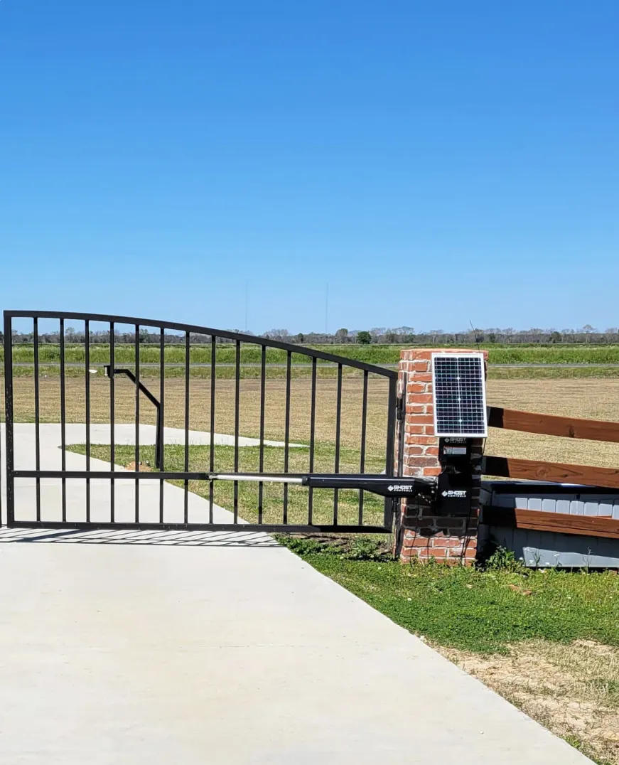A driveway gate with a solar-powered opener mounted on the post