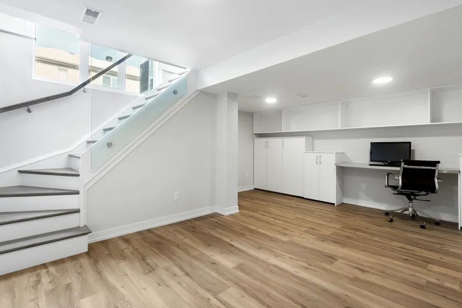 A finished basement with an open staircase and a built-in desk