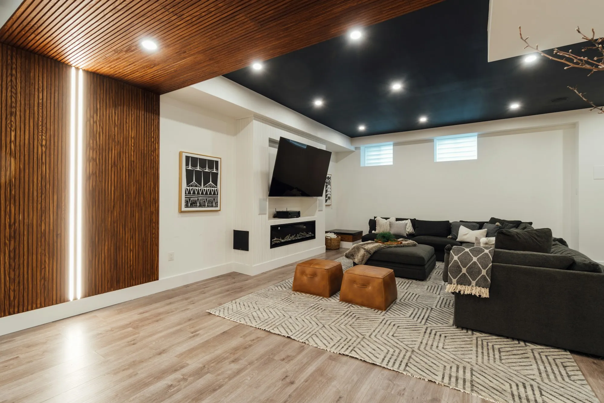 A finished basement with a sectional, TV and linear fireplace