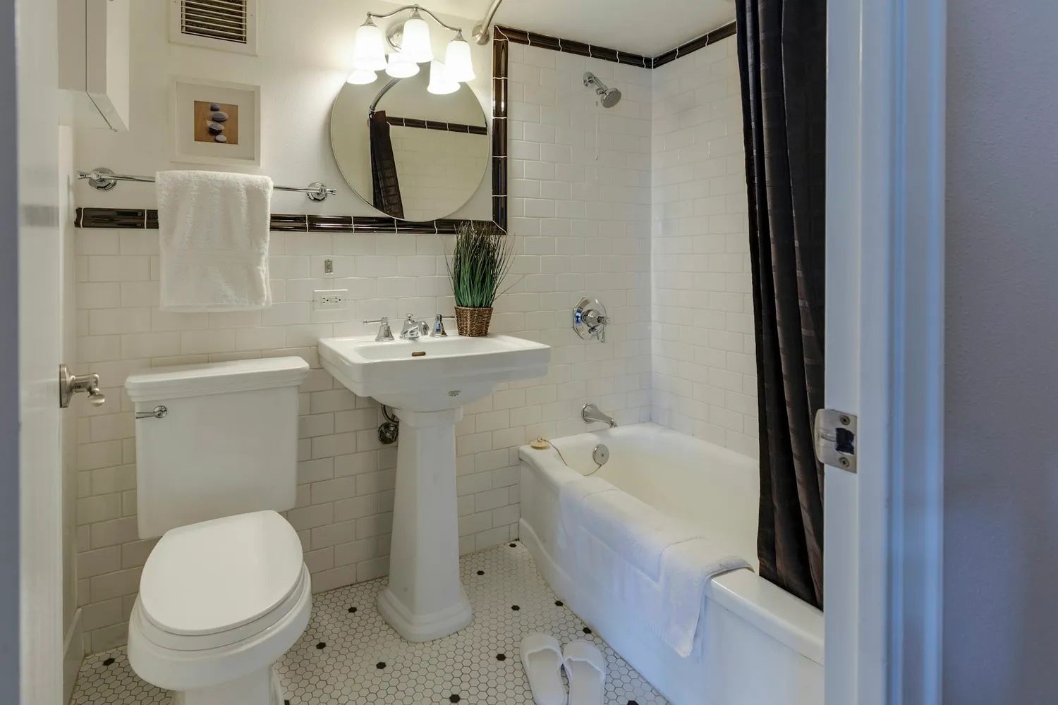 A tired white-tiled bathroom with a pedestal sink and tub