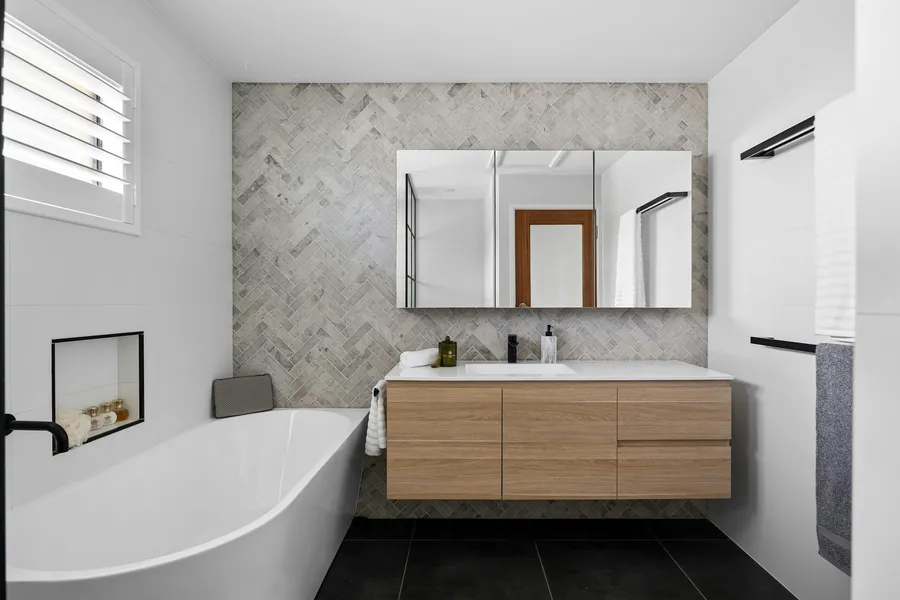 A finished bathroom with a tub and a wood vanity