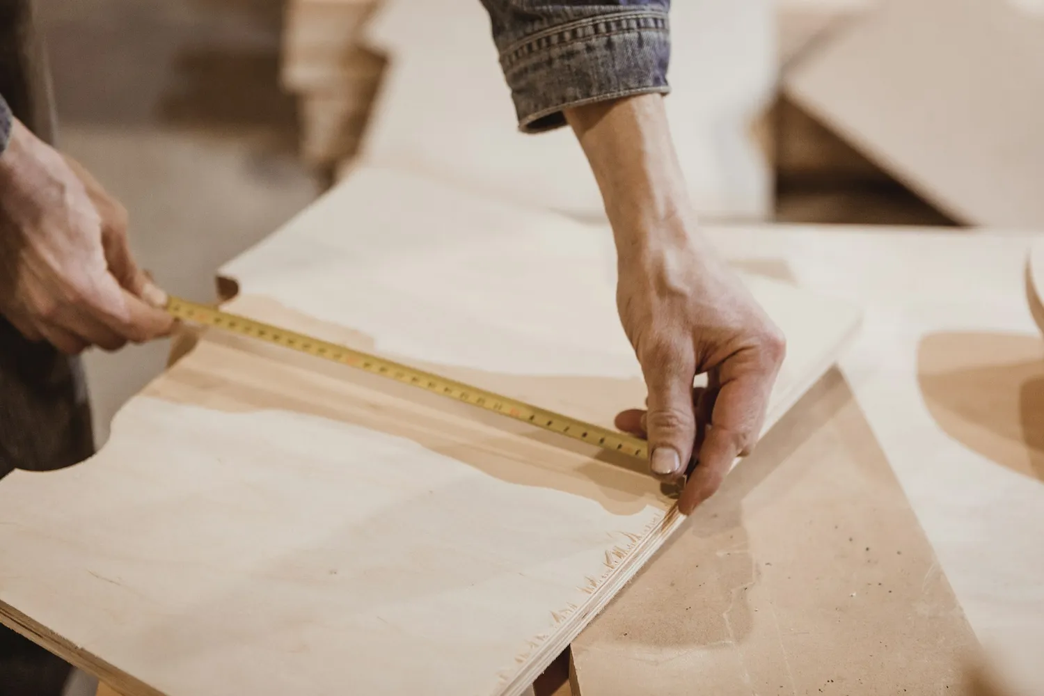 Hands measuring a cabinet panel with a tape