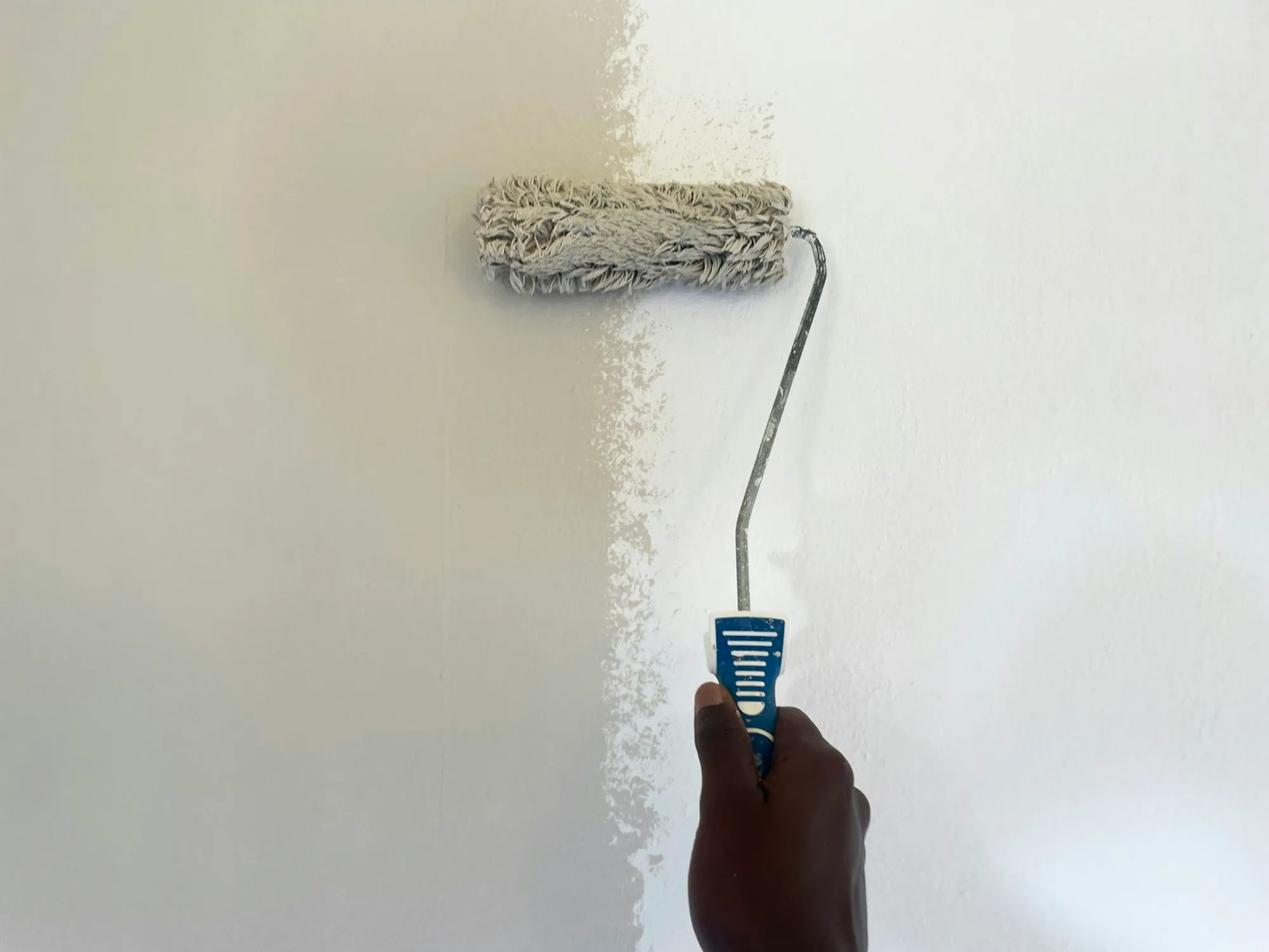 A roller applying paint to an interior wall