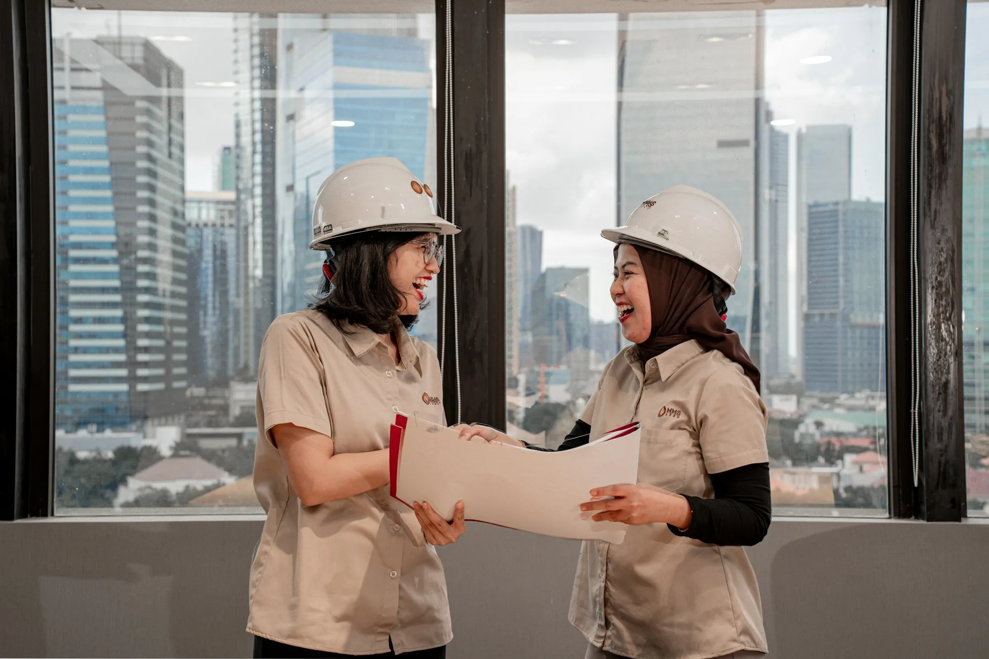 Two people in hard hats reviewing construction drawings on site