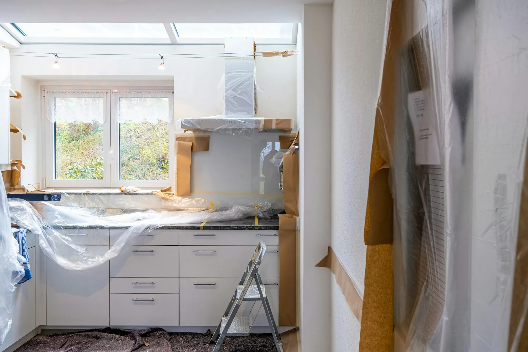 A kitchen mid-renovation, new cabinets wrapped in plastic