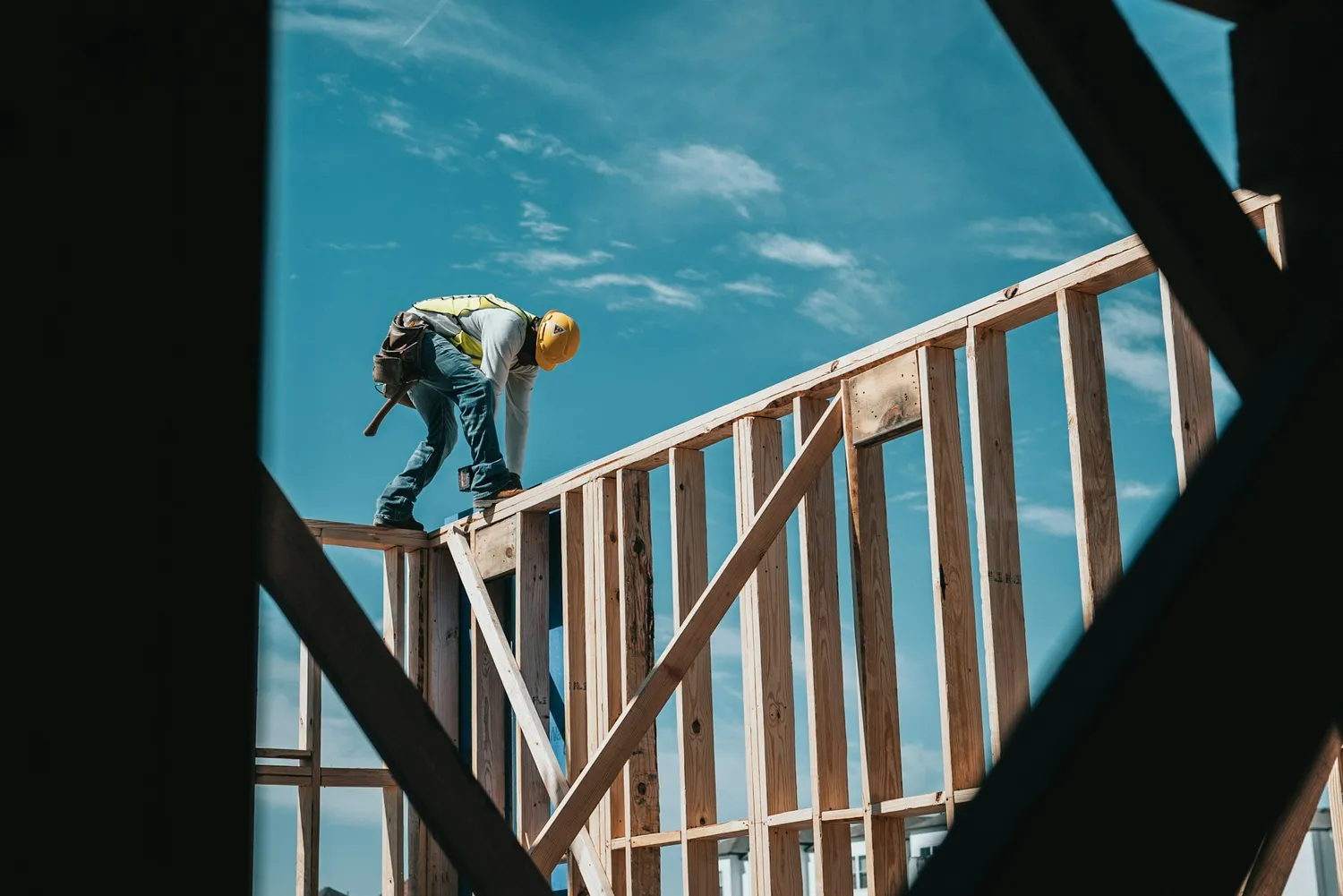 Framer working on top of a wood-framed wall
