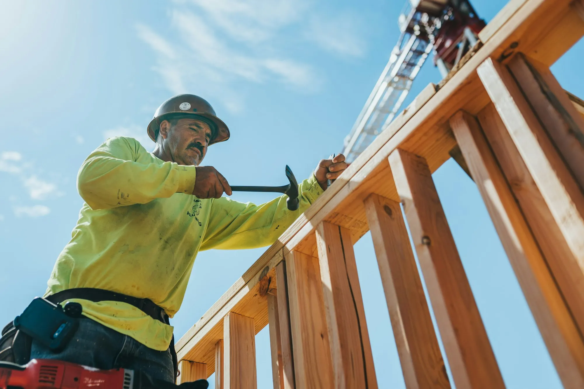 A framer nailing a wood-stud wall