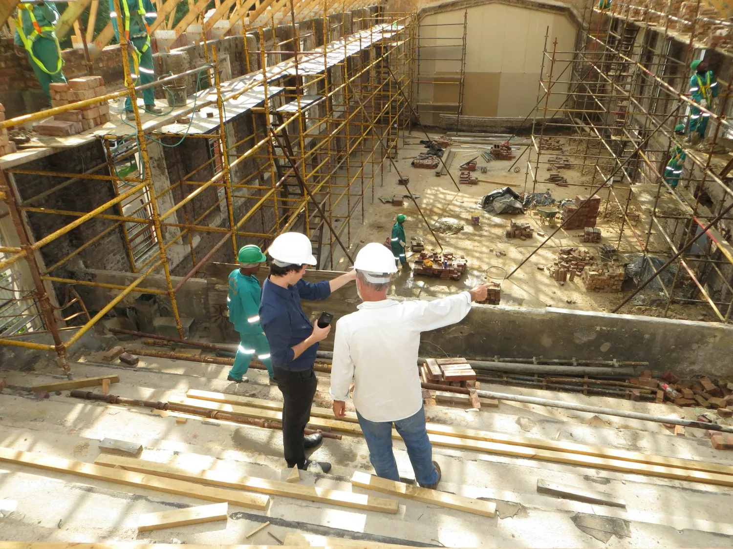 Two supervisors in hard hats reviewing work on a scaffolded site