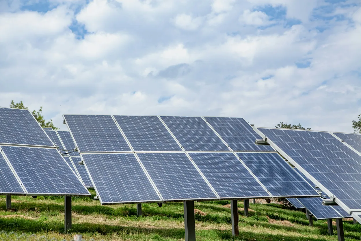A field of solar panels under a cloudy sky
