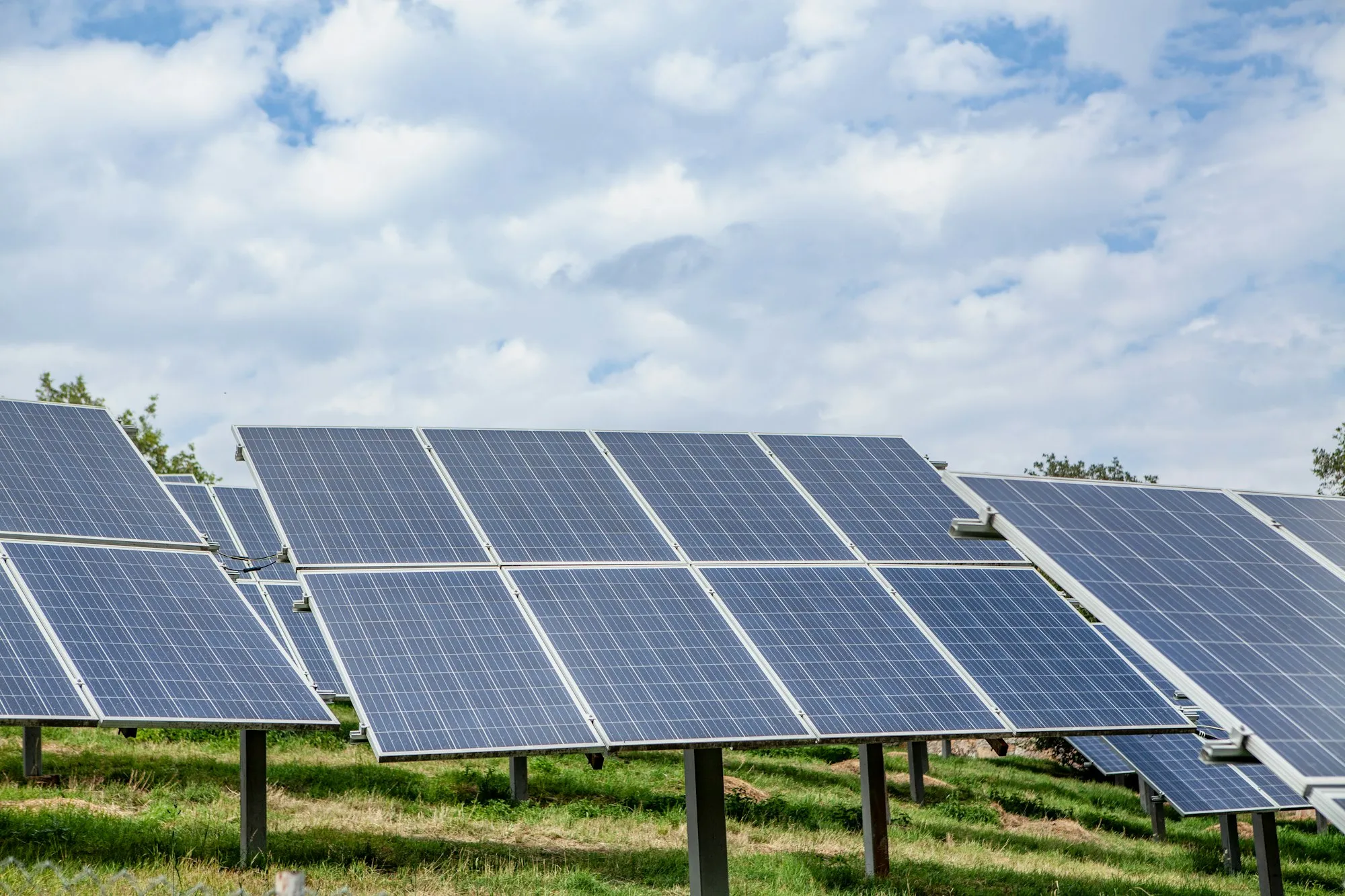 A field of solar panels under a cloudy sky