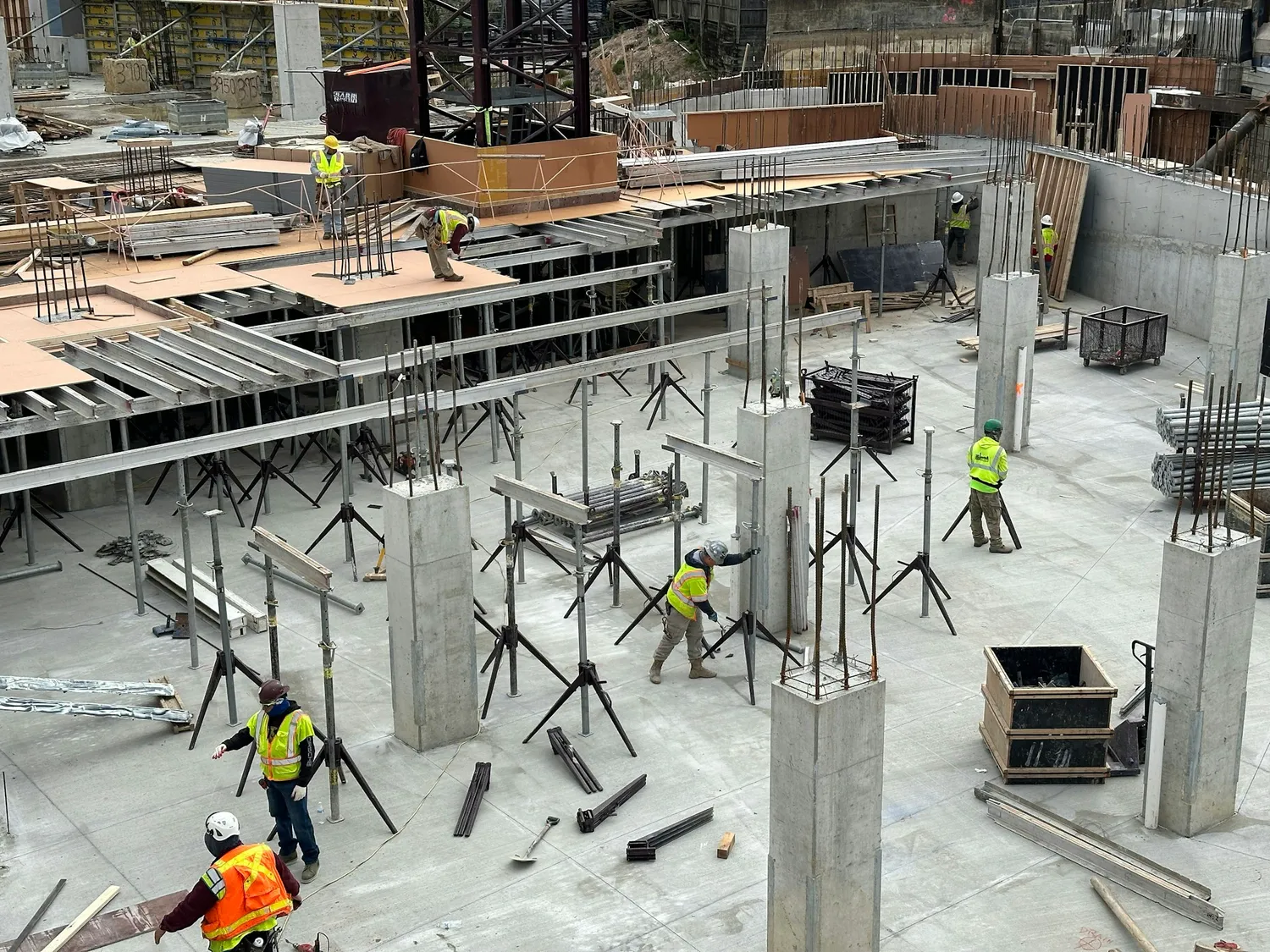 A crew working across a concrete floor among columns and formwork
