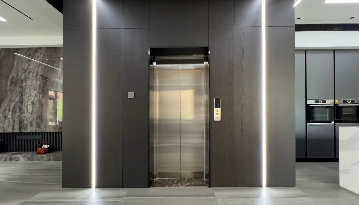 Stainless steel lift doors set into a dark panelled wall