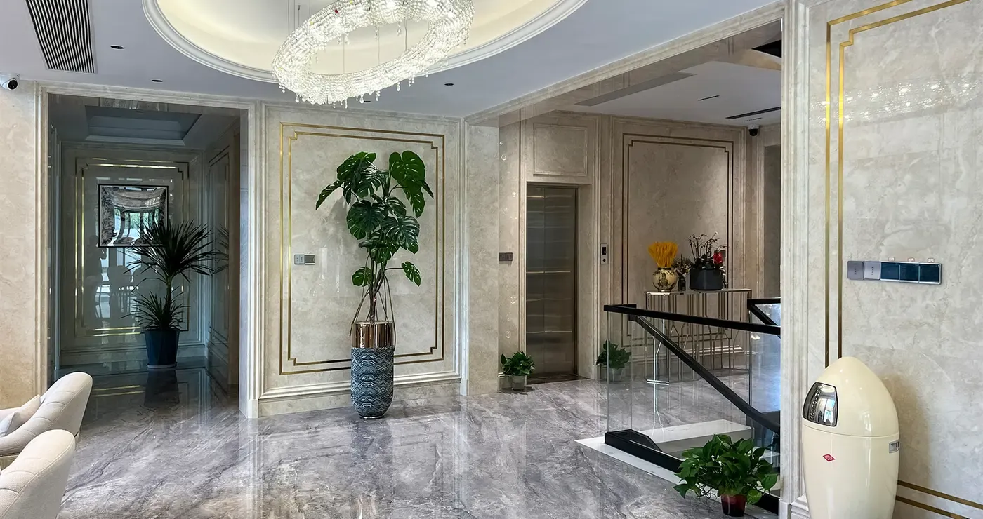 Home lift beside a marble entrance hall with an open stair