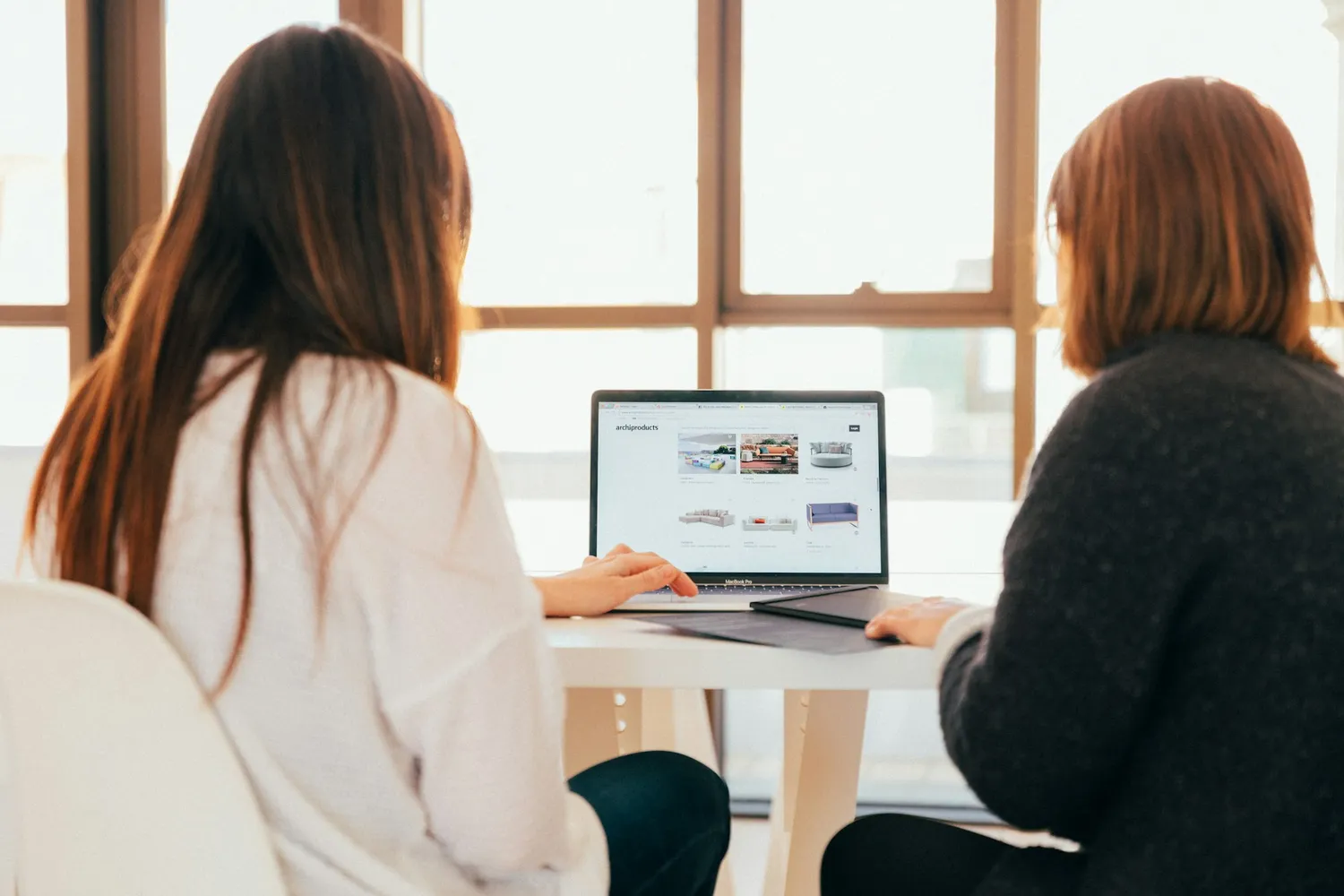 Two people reviewing a website on a laptop