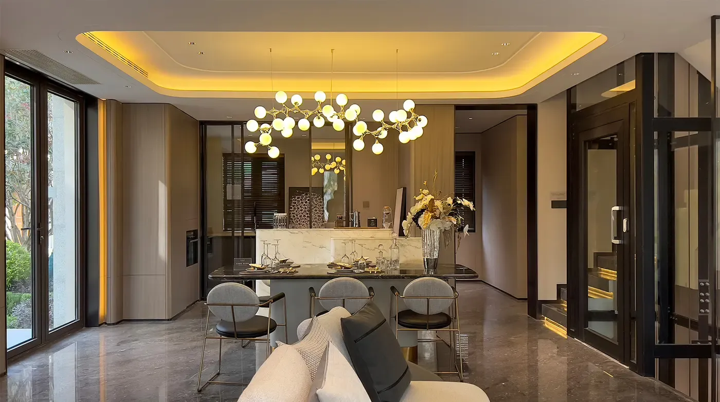Home elevator installed off an open-plan dining area with pendant lights